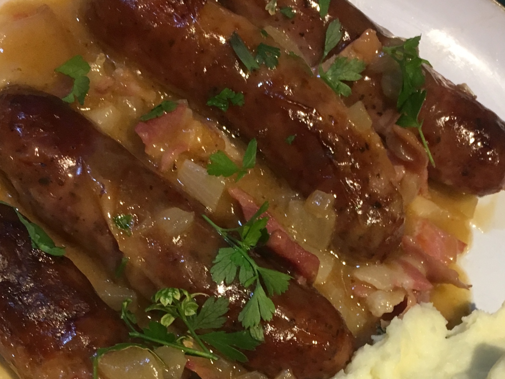 Sausages braised with bacon and cider